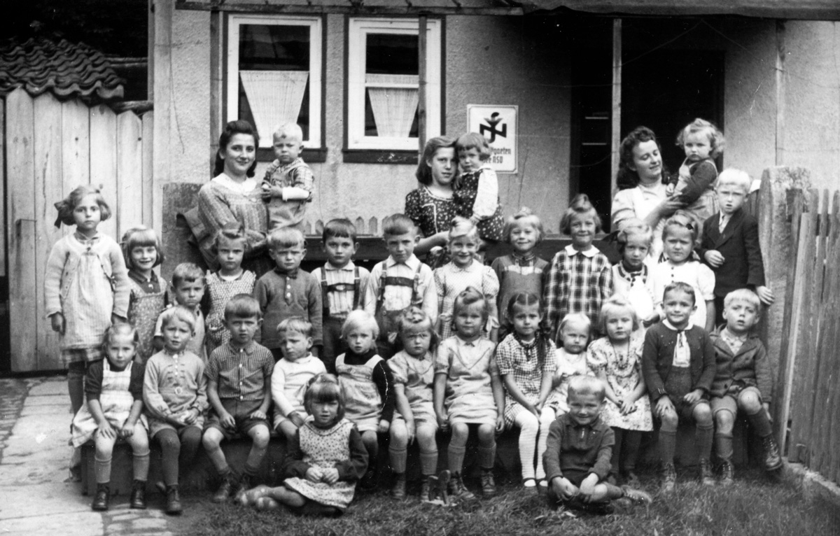 Das Foto zeigt die Kindergartenkinder mit ihren Betreuerinnen vor dem Kindergarten im Jahr 1944. Das Haus stand auf dem Grundstück an der heutigen Adresse „Wetzloserstraße 6“.